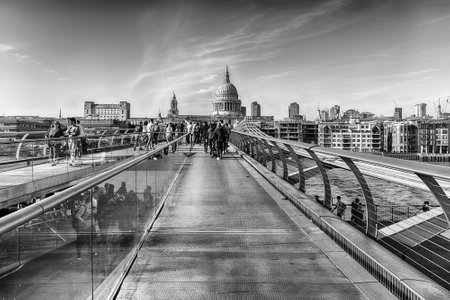 LONDON - APRIL 16, 2022: Walking on the Millennium Bridge, a steel suspension bridge for pedestrians crossing the River Thames in London, England, UKのeditorial素材