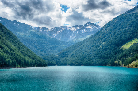 Turquoise water reflecting the blue sky of a sunny summer day at Lake Vernago in Trentino Alto Adige, Italyの写真素材