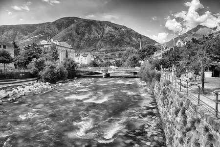 The Passirio River is flowing through the city center of Merano, a famous spa town in South Tyrol, Italy, surrounded by mountainsの写真素材