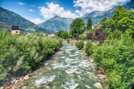 The Passirio River is flowing through the city center of Merano, a famous spa town in South Tyrol, Italy, surrounded by mountainsの写真素材