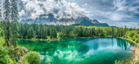 Panoramic view of the emerald green Lake Carezza reflecting the Latemar mountain in the Italian...