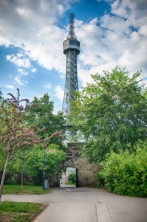 The Petrin lookout tower is standing tall on a partly cloudy day in Prague, Czech Republic
