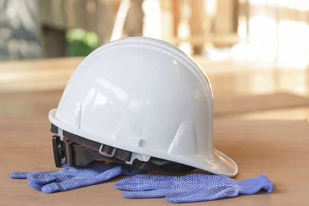 White safety helmet and blue gloves on the wooden floor.の写真素材