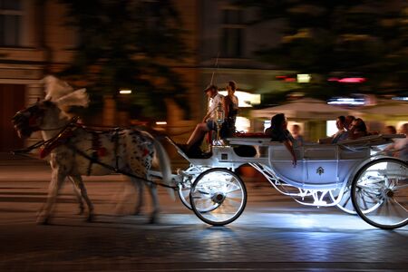 The touristic place in Europe. Tourists are exploring night Krakow by riding in the carriage.