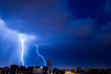 Bright flash of powerful lightning in the city at nighttime.の写真素材