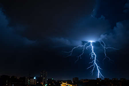 Bright flash of powerful lightning in the city at nighttime.の写真素材