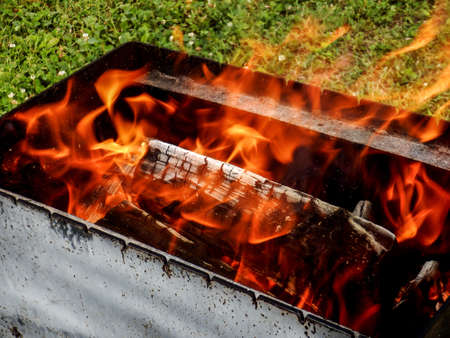 Burning wood in a barbecue grill. Open flames. Cooking outdoors.の写真素材