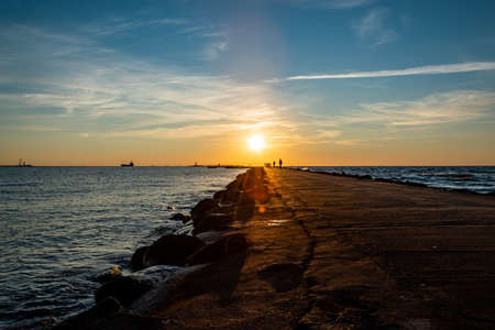 Colourful sunset with golden sun rays on the sea. View on the pier and the bay.の写真素材