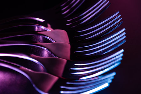Set of forks in the dark with blue and red coloured gradient led light.
