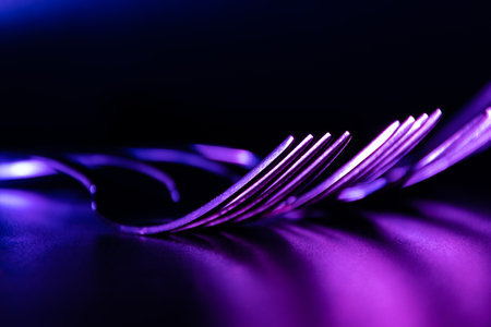 Set of forks in the dark with blue and violet coloured gradient led light.