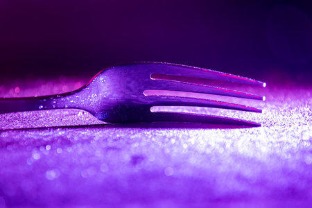 Single fork in the dark illuminated with colourful gradient LED light.の写真素材
