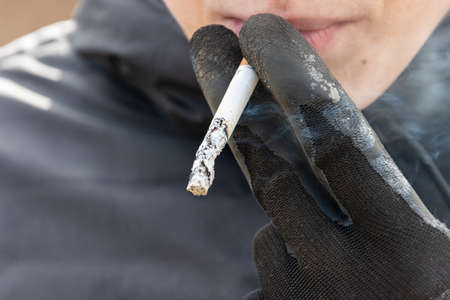 Young man is holding cigarette and smokes it.
