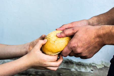 Hands of a child take a bun from the hands of an adult. Peace. Sadnessの写真素材