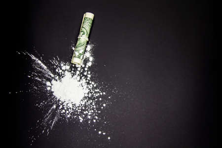 The Dangerous Cocaine with one dollar. Heroine on black background.