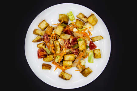 Salad with meat of pig, tomatoes, carrots, cabbage and crackers with bread runner with sauce on the white plate. Healthy and tasty meal for the diet. Delicious breakfast or lunch without GMOの写真素材