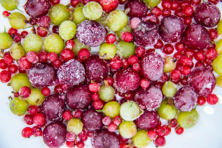 Frozen berries from the freezer. Background with frozen cherries, currants and gooseberries. Healthy...