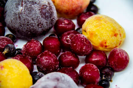 A Berry mix from frozen currant, apricot, plum, cherry. A Frozen Berries from freezer. A sweet background with frozen plum, currant, apricot and cherry. A healthy Berries on the background.の写真素材