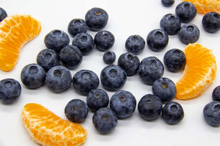 Fresh blueberry  with mandarin slices on white background. A composition of the blueberries and mandarin pieces which is organic and healthy. The berries and fruit full of vitamins.の写真素材
