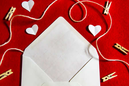 A red background from felt. A composition from heart, thread and clothespins. Frame from envelope for writing. Background with place for write for valentines day and christmas.の写真素材