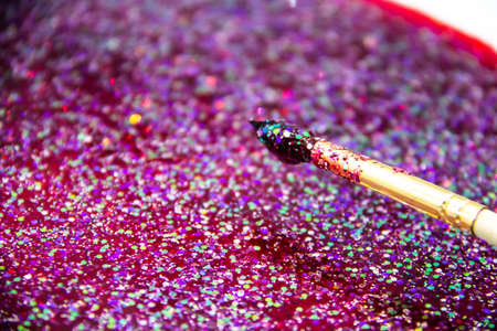 the abstract background with sparkles, glitters and painting brush. Paint brush with glitter in red liquidの写真素材