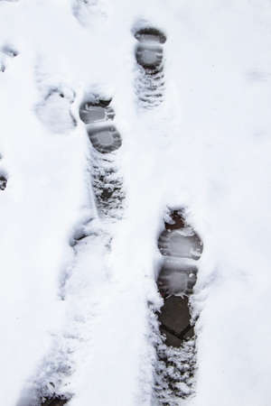 A steps against snow background. footprints on white snow background of boots. Human traces on snow.