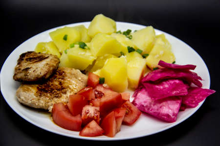Mini steaks of meat with potatoes, tomatoes and pickled cabbage name Pelyustka on white plate. Healthy breakfast with meat, boiled potatoes, tomatoes and red pickled cabbage. Delicious meal for lunchの写真素材