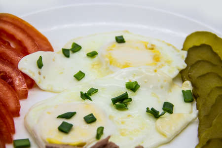 Delicious fresh tuna with eggs, tomatoes, cucmbers with green onion at the morning. Healthy and diet breakfast with tuna, eggs and vegetables on the white plate against white backgroundの写真素材
