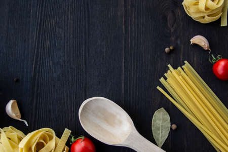 Cooking food background with free space for text. Composition with spaghetti, tomato, eggs, garlic, bay leaf over the wood background. Ingredients for cooking with copy space. Top view for the designの写真素材