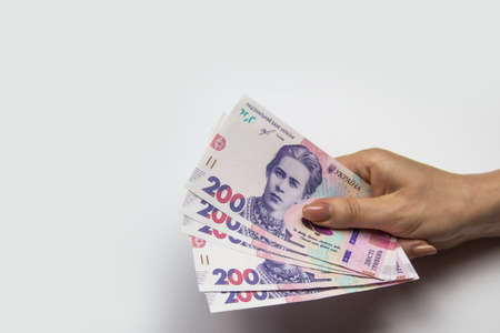 Female hand holds a thousand hryvnia. Ukrainian currency with woman's hand against a white background. One thousand hryvnia with two hundred hryvnia five bills. Ukrainian money.  Banknotes of Ukraineの写真素材