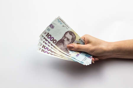 Female hand holds a five thousand hryvnia. Ukrainian currency with woman's hand against a white background. Five thousand hryvnia with one thousand hryvnia five bills. Ukrainian money. Banknotesのeditorial素材