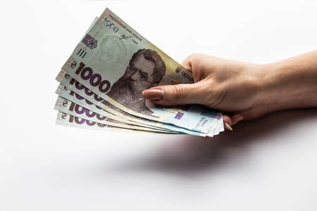 Female hand holds a five thousand hryvnia. Ukrainian currency with woman's hand against a white background. Five thousand hryvnia with one thousand hryvnia five bills. Ukrainian money. Banknotesのeditorial素材