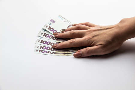 Female hand holds a five thousand hryvnia. Ukrainian currency with woman's hand against a white background. Five thousand hryvnia with one thousand hryvnia five bills. Ukrainian money. Banknotesのeditorial素材