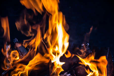 Fire on a dark background. Fire from firewood close up. Flaming burning sparks close-up, fire patterns. Red and orange Infernal glow of fire in the dark.の写真素材