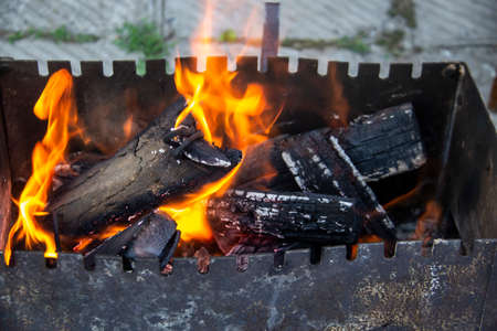 Barbecue grill mangal preparation with roaming fire outside building. Burns a firewood