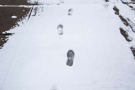 A steps against snow background. footprints on white snow background of boots. Human traces on snow.の写真素材