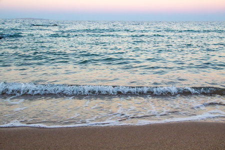 The beach with sea waves running on the sand. Beautiful view on the waves