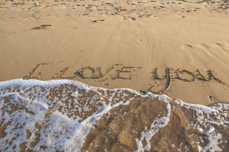 Words I Love You writing on the sand on beach against background. Love letters on the sand with sea...