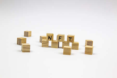Word NFT (non fungible token) written on the wood cubes on white background. Non-fungible tokens concept NFT.の写真素材