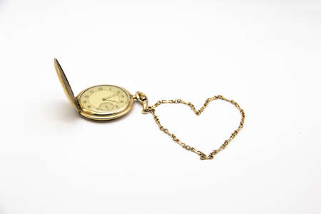 Vintage golden old pocket watch on white background. The chain lies in the form of a heart.の写真素材