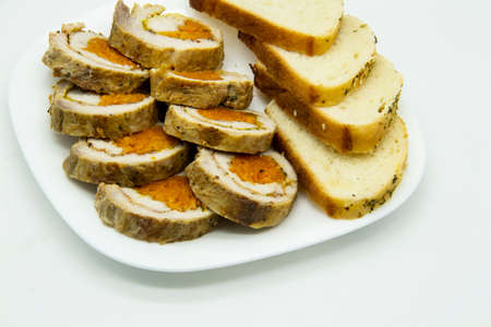 Meatloaf with carrots, sliced â€‹â€‹on the plate with pieces of bread on white background
