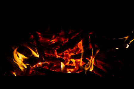 Red coals with fire on a black background. Burning coals and wood in the fire. Burning wood to keep...