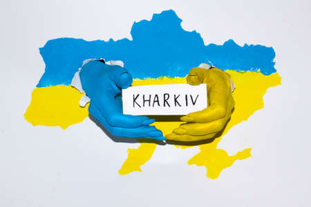 Drawing map of Ukraine in blue yellow color with female hands hold the banner with word Kharkiv. Female hands painted in color with flag of Ukraine.の写真素材
