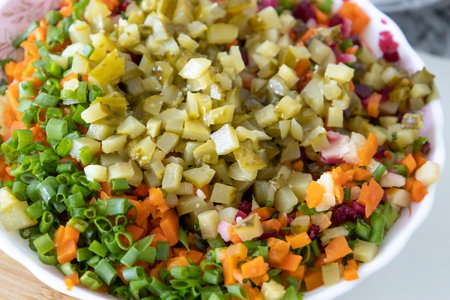 A tasty salad named Vinaigrette - a traditional Ukrainian and Russian vegetable salad. Vegetarian dish. Vegan food with green onion, boiled potatoes, carrots, beet. Salad backgroundの写真素材