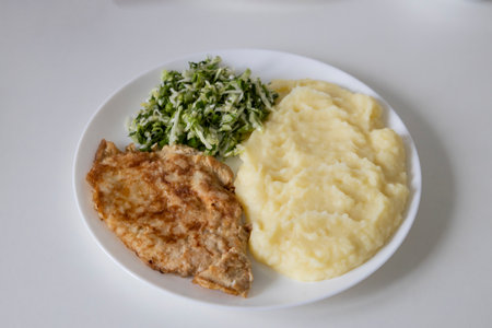 A delicious breakfast or lunch with mashed potatoes, chop with salad - green onions and green young cabbage, parsley on the white plate.の写真素材