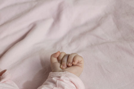 A tiny fist and hand against a soft pink backgroundの写真素材