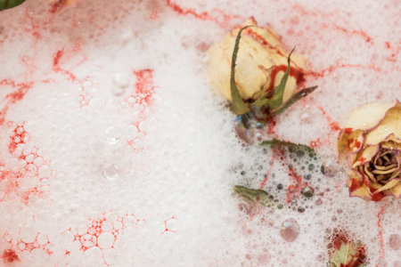 Dry flowers with foam and water. Red color between bubbles from the soap. Roses in white foam
