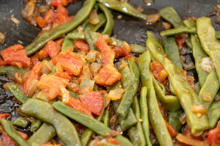 Fried green beans with tomato and onion pieces. Tasty meal with French bean on dinner or lunch on...