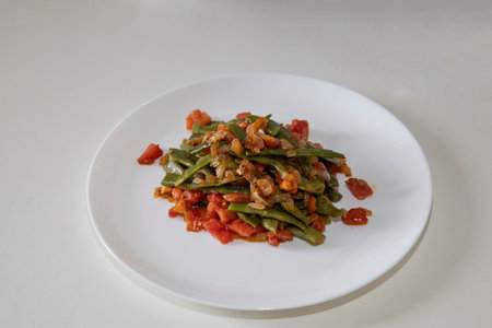 Fried green beans with tomato and onion pieces. Tasty meal with French bean on dinner or lunch on...