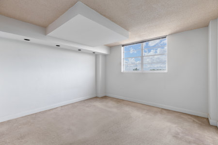 empty room with window with sky in the background, white walls, carpeted floor and beige ceiling, wall with 4 lights, ideal shot for office or bedroom renderingの写真素材