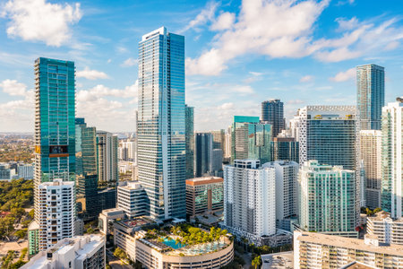 aerial view of modern Miami buildings, skyscrapers, pool areas with tropical plants, blue sky
